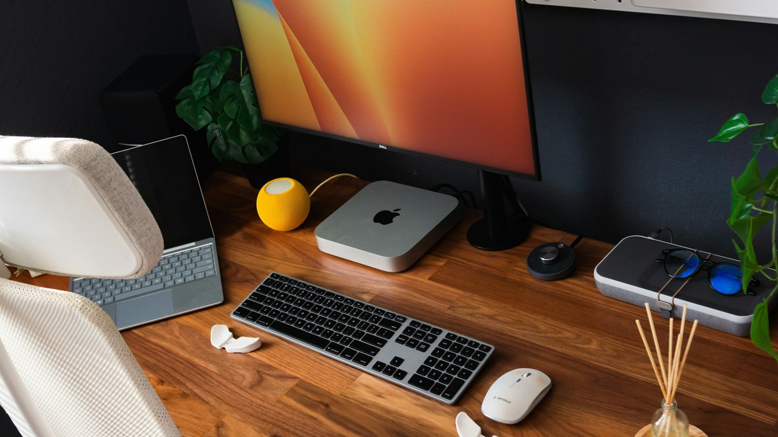 Setup organizado com Mac Mini, monitor, teclado e mouse sobre uma mesa